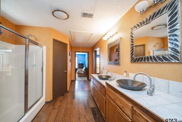 bathroom with a stall shower, visible vents, a sink, and wood finished floors