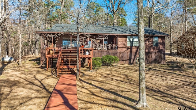 view of front of property with covered porch, a shingled roof, and stairway