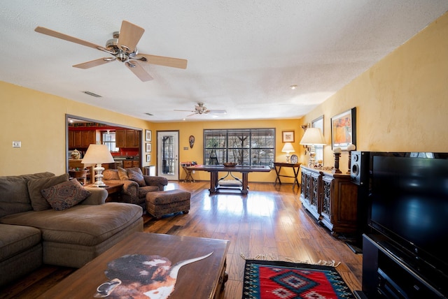 living area featuring visible vents, a textured ceiling, and wood finished floors