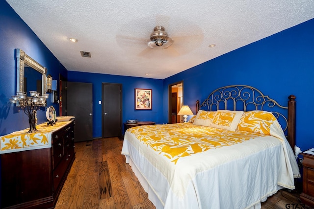 bedroom featuring a ceiling fan, visible vents, a textured ceiling, and wood finished floors