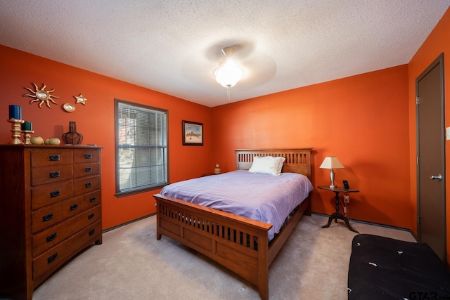 bedroom with a textured ceiling, ceiling fan, and light colored carpet