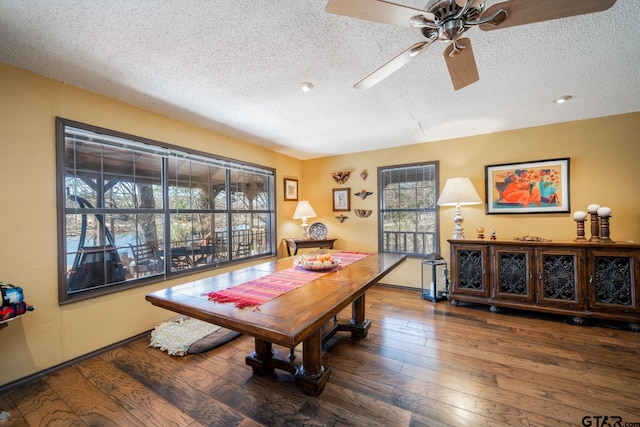 dining area with a textured ceiling and dark wood-style flooring