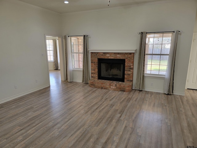 unfurnished living room featuring light wood-type flooring, a wealth of natural light, and a brick fireplace