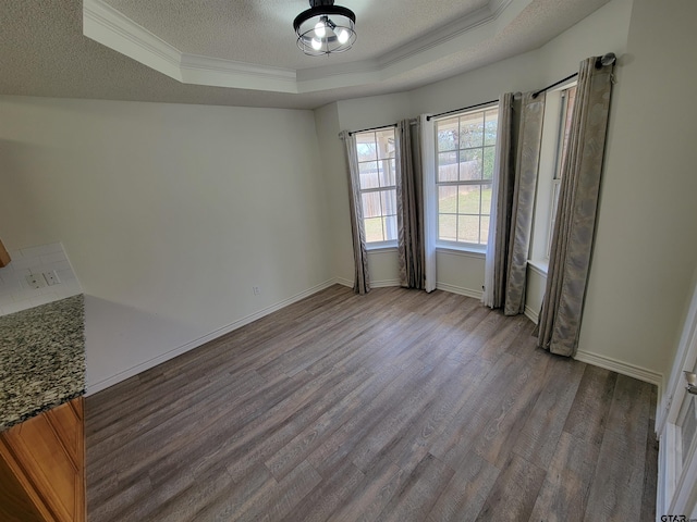 unfurnished room featuring light hardwood / wood-style floors, crown molding, a textured ceiling, and a tray ceiling