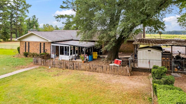 back of property with a storage shed, a sunroom, and a yard