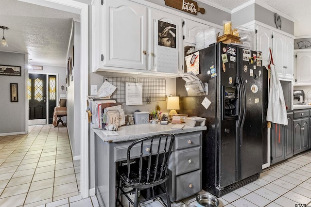 kitchen featuring black fridge, ornamental molding, light tile patterned flooring, a textured ceiling, and white cabinets