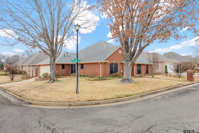 view of front of house featuring an attached garage, brick siding, a shingled roof, driveway, and a front lawn