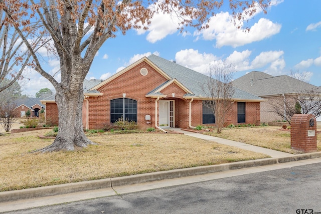 view of front of house with brick siding, roof with shingles, and a front yard