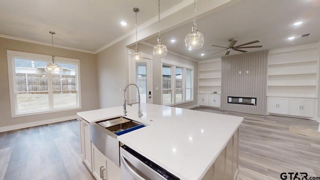 kitchen featuring white cabinetry, stainless steel dishwasher, hanging light fixtures, and a center island with sink