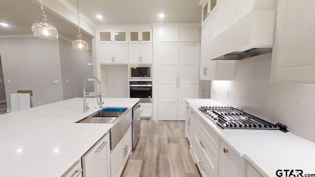 kitchen featuring white cabinetry, sink, hanging light fixtures, stainless steel appliances, and custom range hood