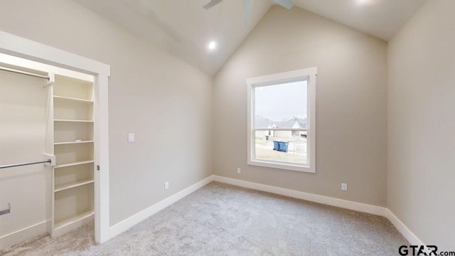 carpeted spare room featuring lofted ceiling and a walk in closet