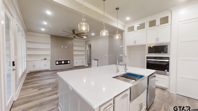 kitchen with wall oven, a center island with sink, and white cabinets