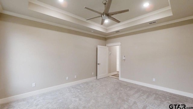 carpeted spare room featuring crown molding, a raised ceiling, and ceiling fan