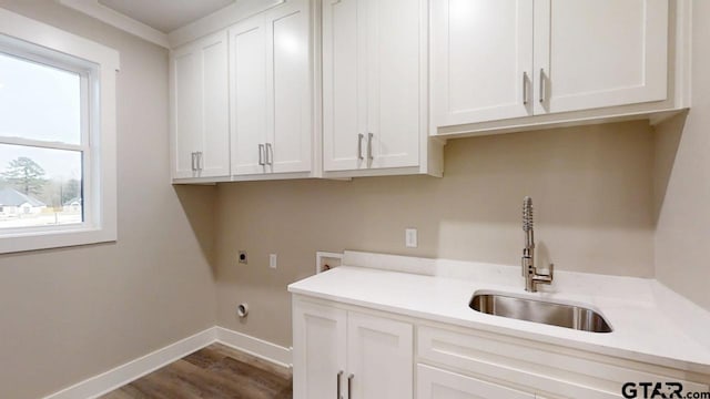 laundry room featuring sink, hardwood / wood-style flooring, electric dryer hookup, hookup for a washing machine, and cabinets