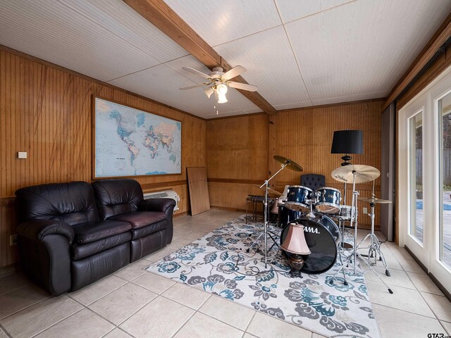 tiled living room with beamed ceiling, ceiling fan, and wooden walls