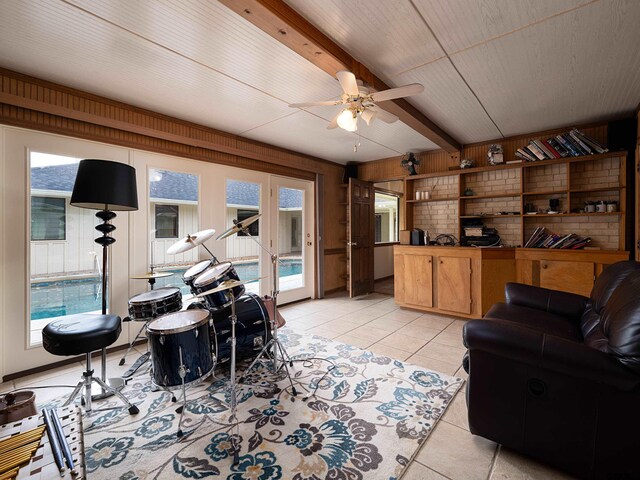 tiled living room featuring a healthy amount of sunlight, beam ceiling, and wooden walls