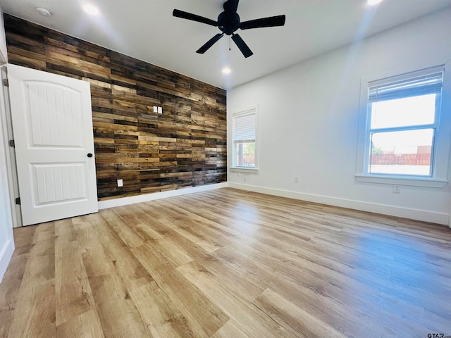 unfurnished room featuring a wealth of natural light, wooden walls, and light hardwood / wood-style flooring