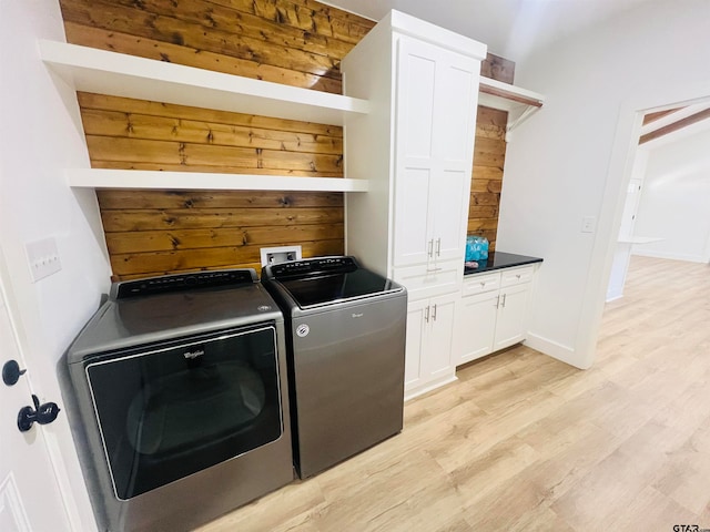 clothes washing area with cabinets, washer and dryer, and light hardwood / wood-style flooring