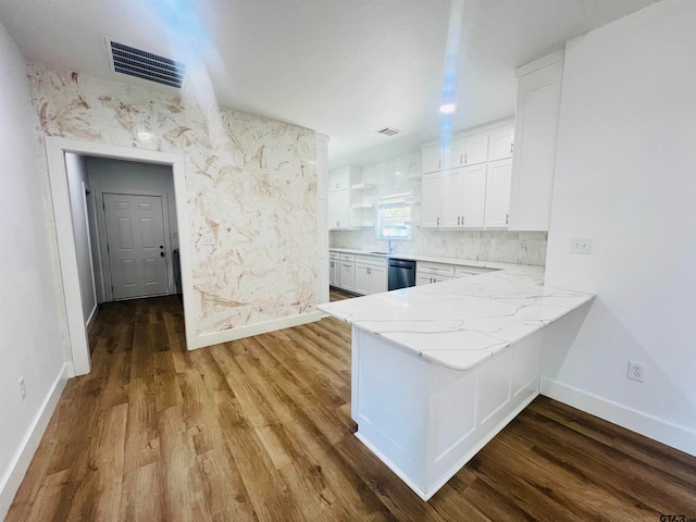 kitchen with dishwasher, kitchen peninsula, wood-type flooring, and white cabinets