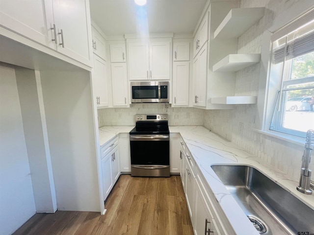 kitchen featuring stainless steel appliances, white cabinetry, sink, light stone countertops, and hardwood / wood-style floors