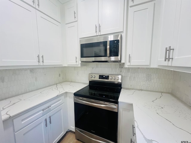 kitchen with white cabinets, appliances with stainless steel finishes, and light stone counters