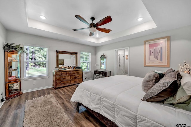 bedroom with a raised ceiling, dark wood-type flooring, and ceiling fan