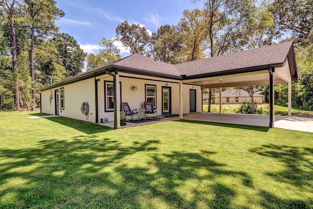 rear view of house with a lawn and a carport