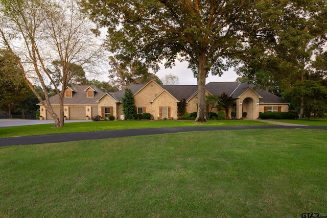 view of front of home with driveway, stone siding, and a front lawn