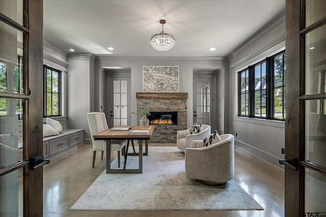 living room featuring a healthy amount of sunlight, an inviting chandelier, a stone fireplace, and ornamental molding