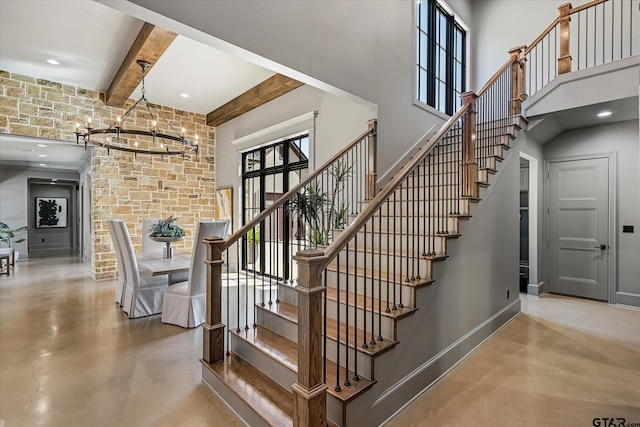 stairway with an inviting chandelier, concrete floors, and beamed ceiling