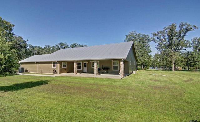 rear view of house featuring brick siding, a lawn, metal roof, and a patio