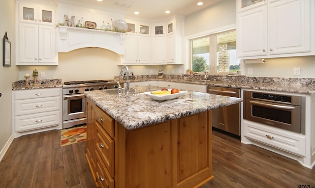 kitchen with sink, white cabinetry, appliances with stainless steel finishes, an island with sink, and light stone counters