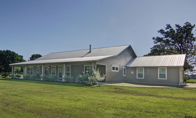 back of property featuring a lawn and metal roof