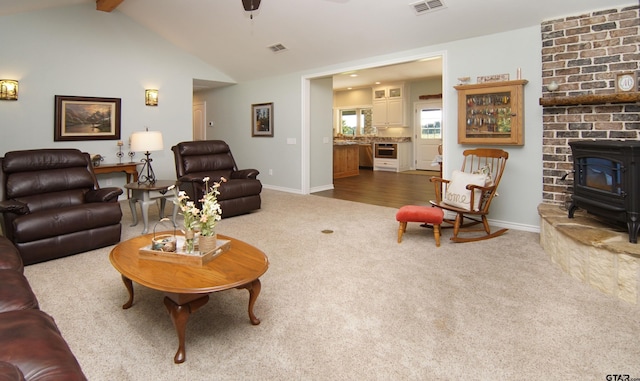 living room with dark colored carpet, visible vents, vaulted ceiling with beams, and a wood stove