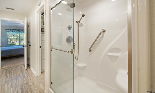 ensuite bathroom with visible vents, a stall shower, ensuite bath, and wood finished floors