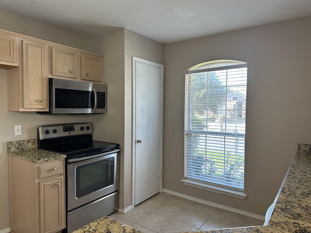 kitchen featuring light stone counters, light brown cabinetry, appliances with stainless steel finishes, and light tile patterned flooring