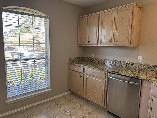 kitchen featuring light stone counters, light tile patterned floors, stainless steel dishwasher, and light brown cabinets