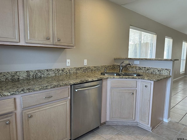 kitchen with kitchen peninsula, light brown cabinets, stainless steel dishwasher, sink, and light stone countertops