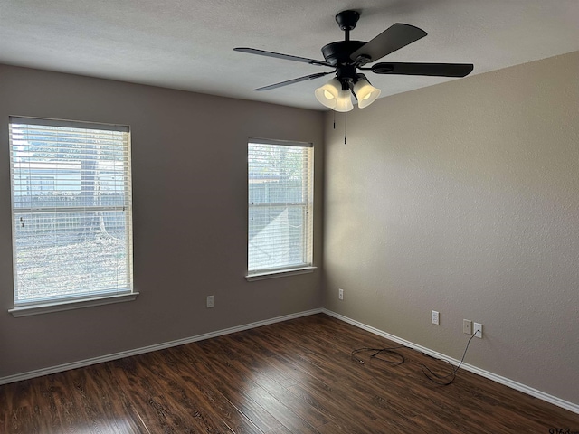 spare room with ceiling fan, a healthy amount of sunlight, and dark wood-type flooring