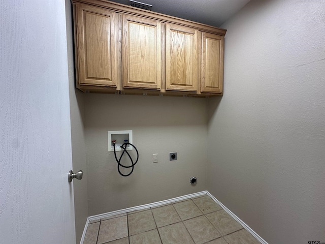 washroom with washer hookup, electric dryer hookup, cabinets, and light tile patterned flooring