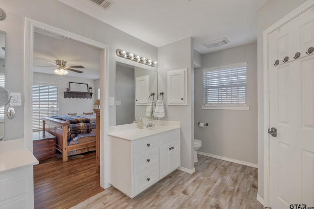 bathroom with hardwood / wood-style flooring, ceiling fan, vanity, and toilet