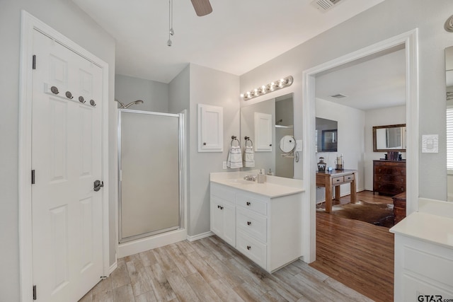 bathroom with ceiling fan, wood-type flooring, an enclosed shower, and vanity