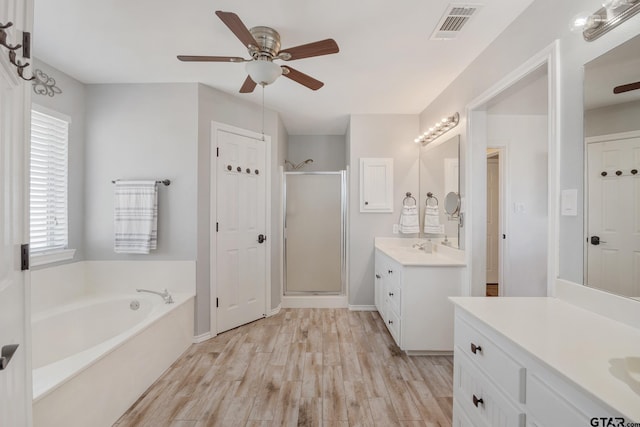 bathroom with wood-type flooring, separate shower and tub, vanity, and ceiling fan