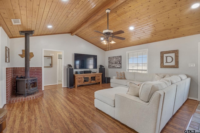 living room featuring wood-type flooring, a wood stove, vaulted ceiling with beams, ceiling fan, and wooden ceiling