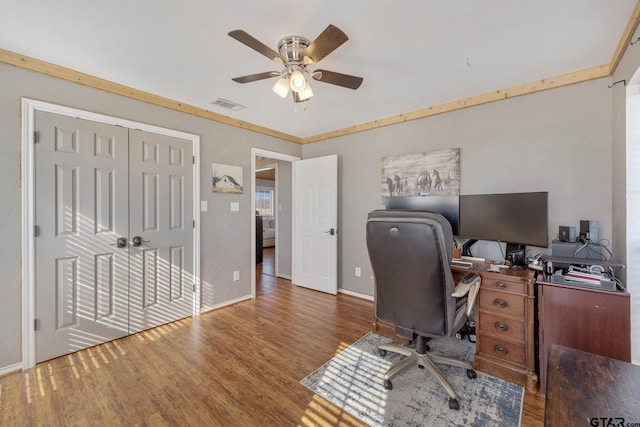 home office with dark wood-type flooring, ornamental molding, and ceiling fan