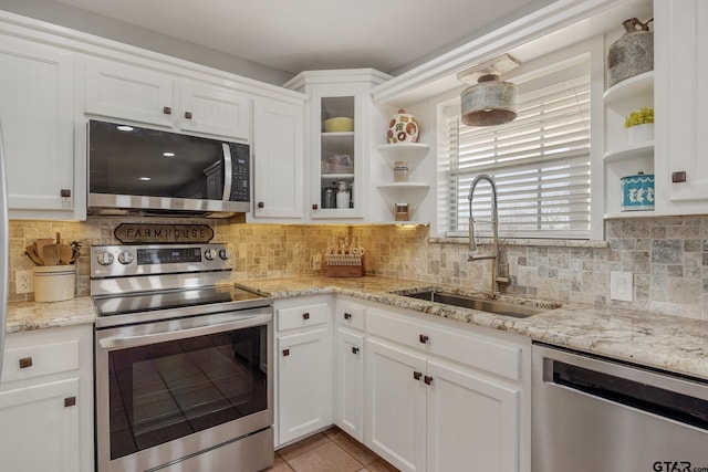 kitchen with sink, appliances with stainless steel finishes, light stone countertops, decorative backsplash, and white cabinets