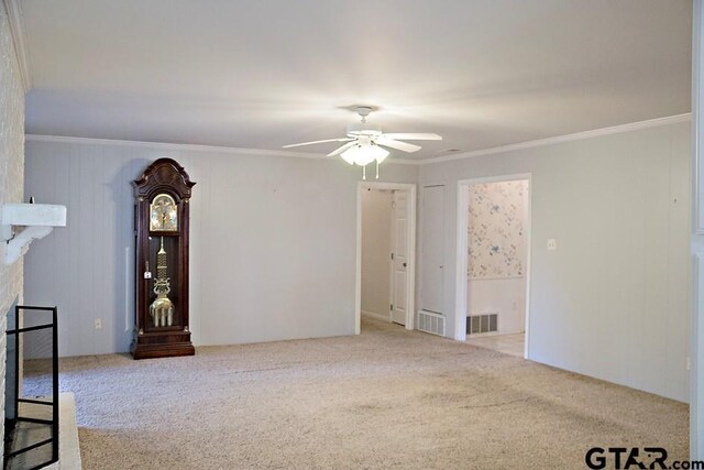 unfurnished living room featuring ceiling fan, ornamental molding, a fireplace, and carpet