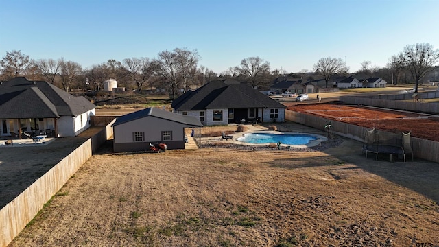 back of house featuring a yard, a fenced in pool, and a trampoline