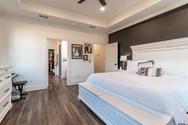 bedroom with dark wood-type flooring, a raised ceiling, and crown molding