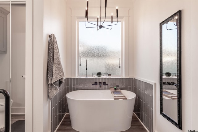 full bathroom with a freestanding tub, tile walls, and wainscoting